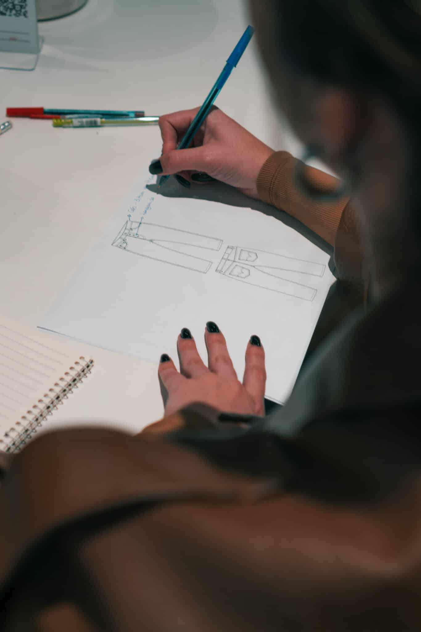 Aluna analisando a ficha técnica de uma calça jeans no ateliê da Escola Casa